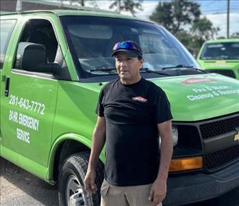 Servpro employee in front of two Servpro work vans 